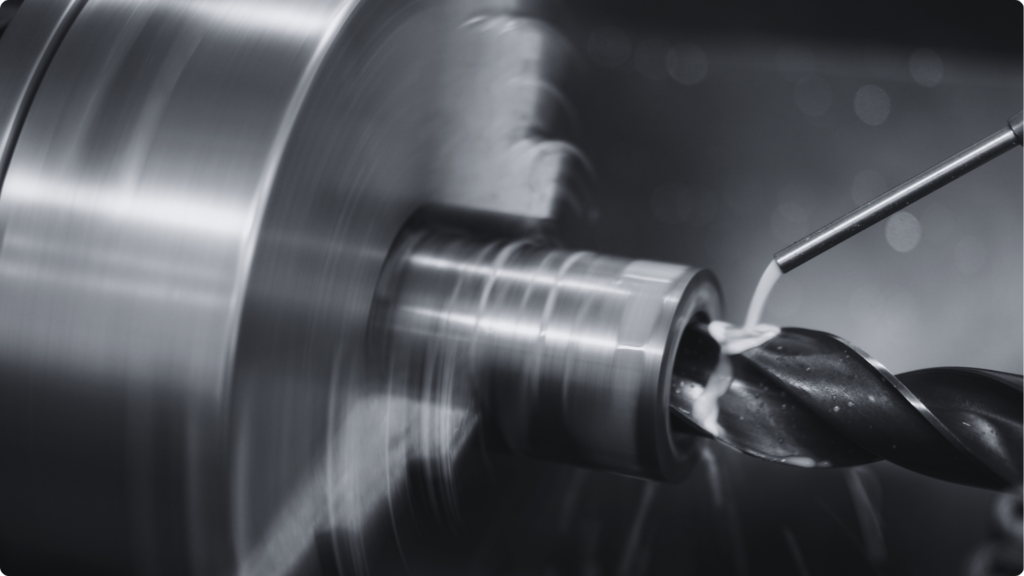 Close-up of a cast part being turned and drilled on a lathe in the Machining step